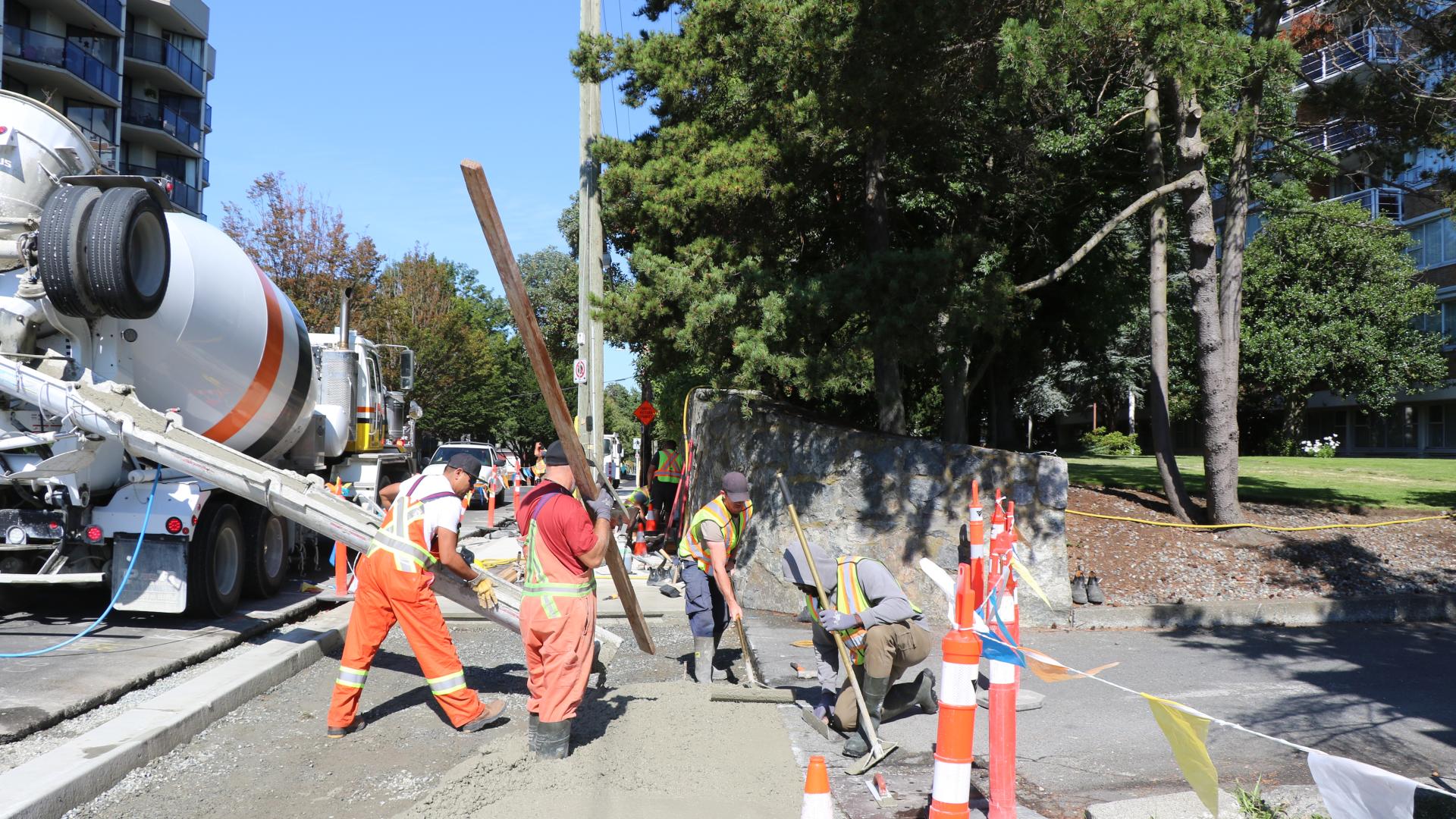 Crews pour concrete from large truck to make a sidewalk