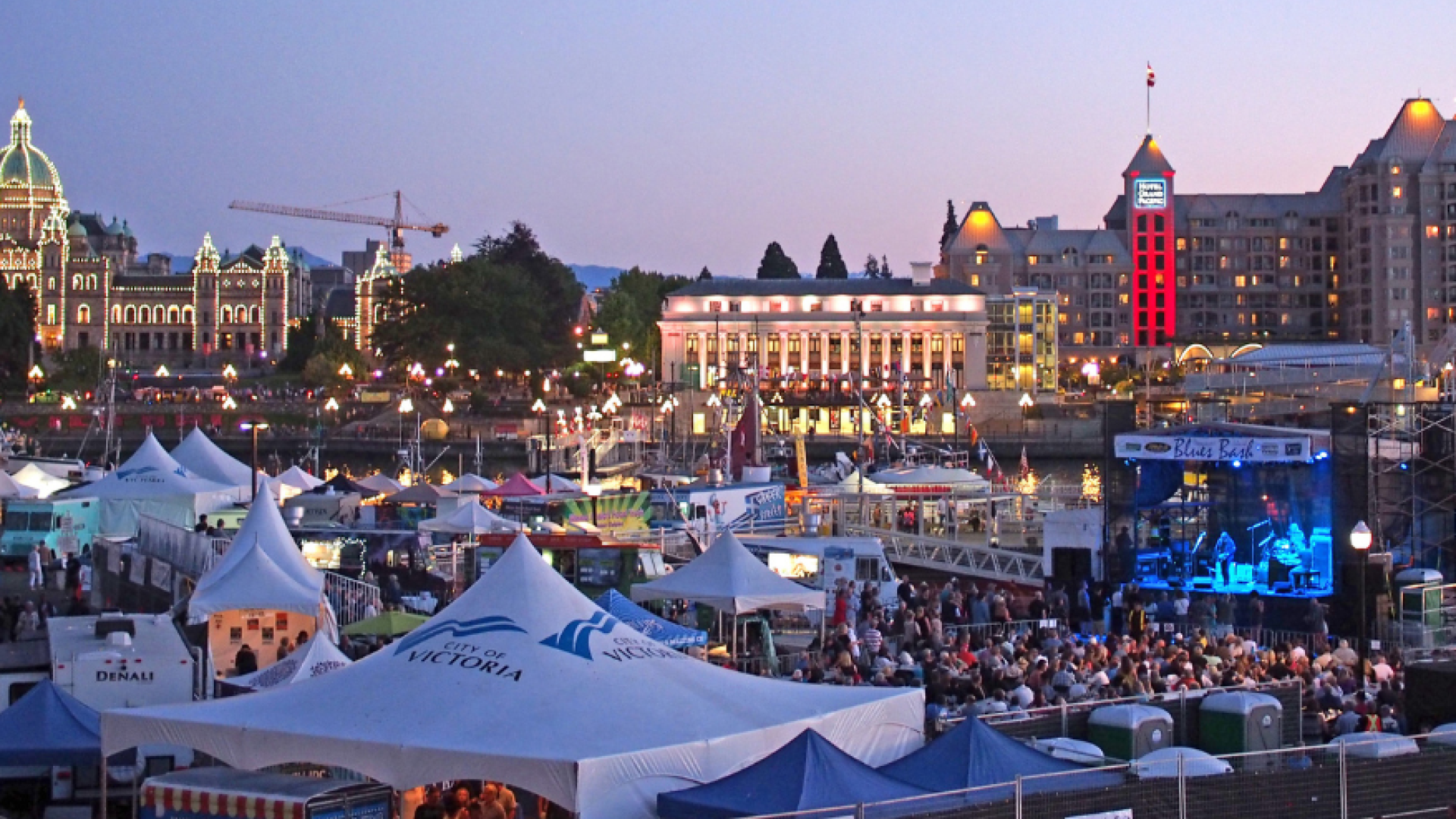 Blues Festival at sunset in Inner Harbour with a main stage at Ship Point and other festive pop-up, white tents.