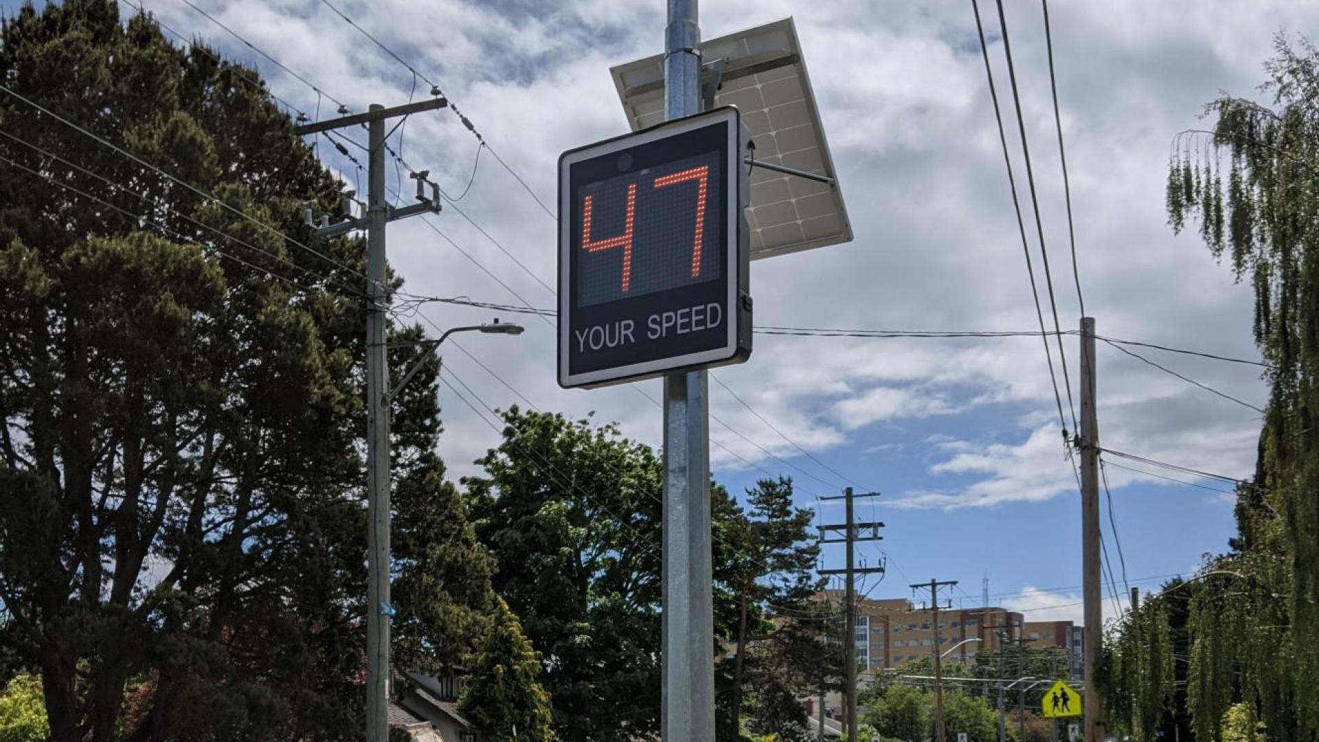 Pole on a street with digital sign showing 47 kilometres per hour