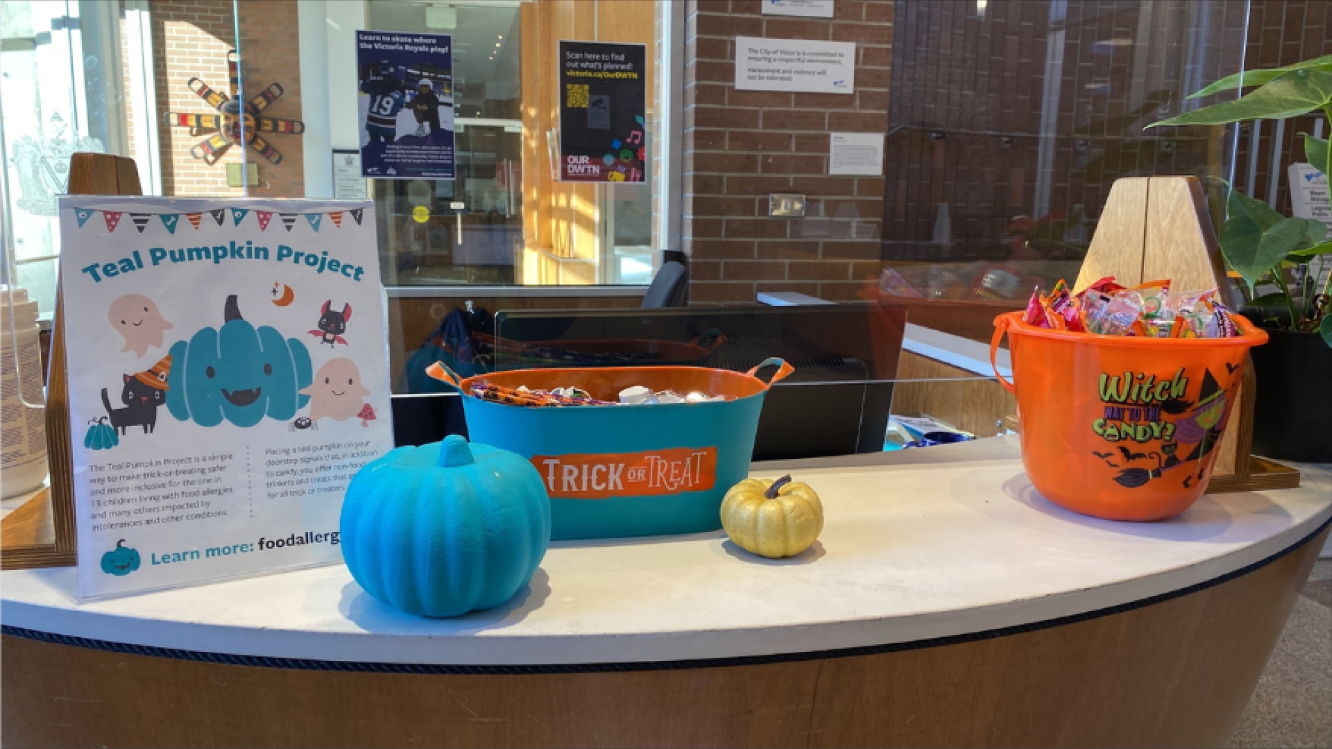 Image of a teal pumpkin with a container of candy and a container of non-food treats, next to a sign that reads Teal Pumpkin Project.