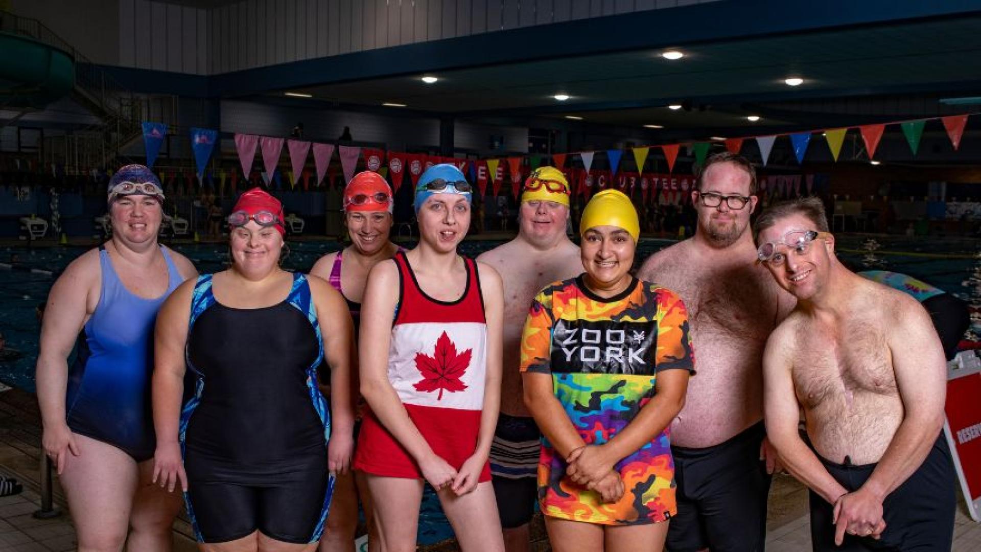a group of people in swimwear smiling in front of swim lanes