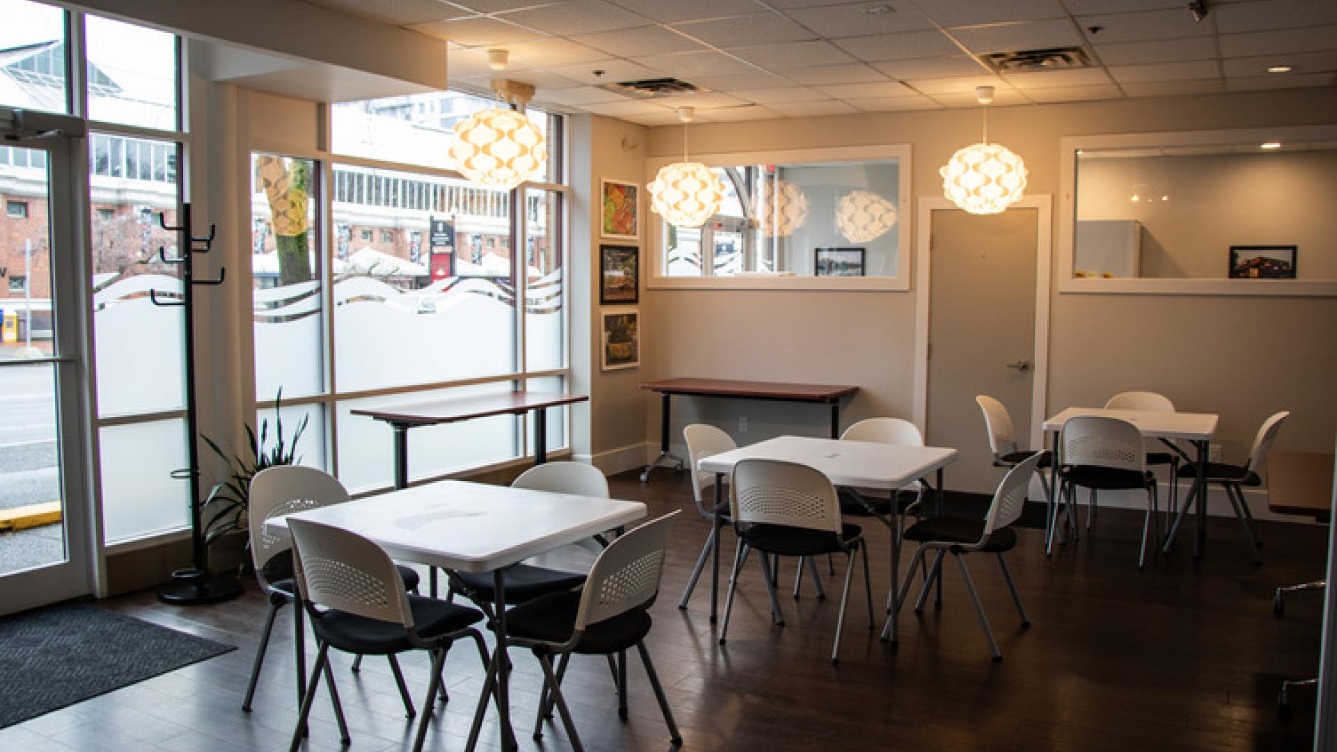 A collection of desks and chairs with large windows and globe style lights