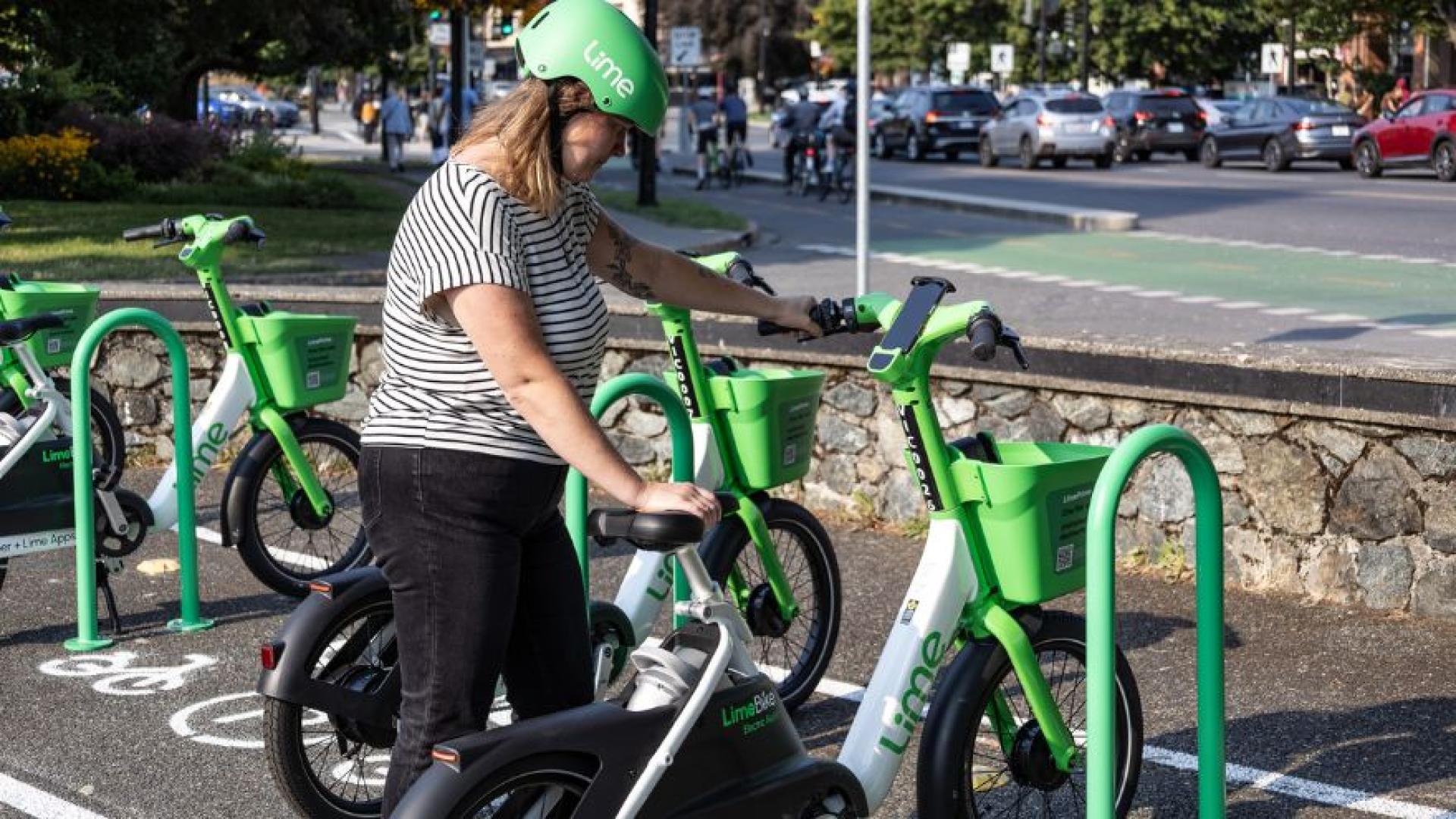 2.	A person wearing a helmet looking down at a Lime bike with Wharf Street in the background.