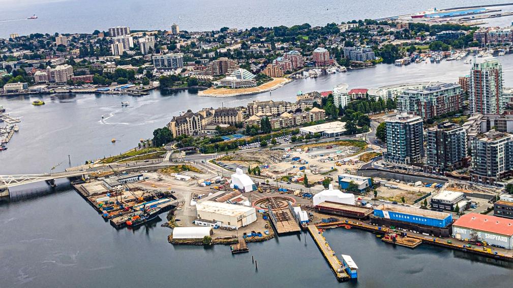 An image on the upper harbour in the foreground with industry and industrial buildings, the Johnson Street Bridge, and the Inner Harbour in the background. 