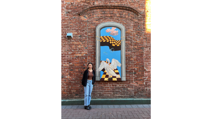 Image of artist Ella Chay standing next to her Commercial Alley artwork panel. 
